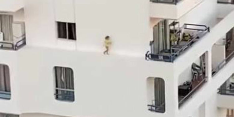 Na imagem é possível ver a criança andando no parapeito do prédio. | REPRODUÇÃO