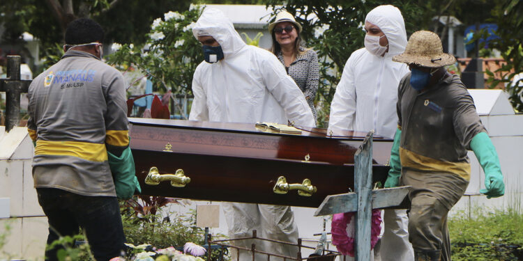 A relative stands at a distance during the burial of Robson de Souza Lopes at Parque Taruma cemetery in Manaus, Brazil, Tuesday, March 31, 2020. According to authorities at the Amazonas Health Secretary, the 43-year-old musician died Monday after being diagnosed with COVID-19. (AP Photo/Edmar Barros)