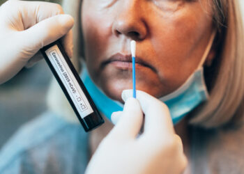 Doctor's hands in protection gloves holds Testing Kit for the coronavirus test