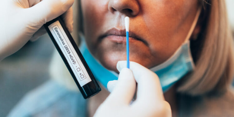 Doctor's hands in protection gloves holds Testing Kit for the coronavirus test