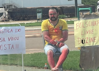 O homem apareceu em vídeos acorrentado a um vaso sanitário, segurando cartazes e pedindo apoio dos motoristas que passavam pelo local. Foto: Reprodução