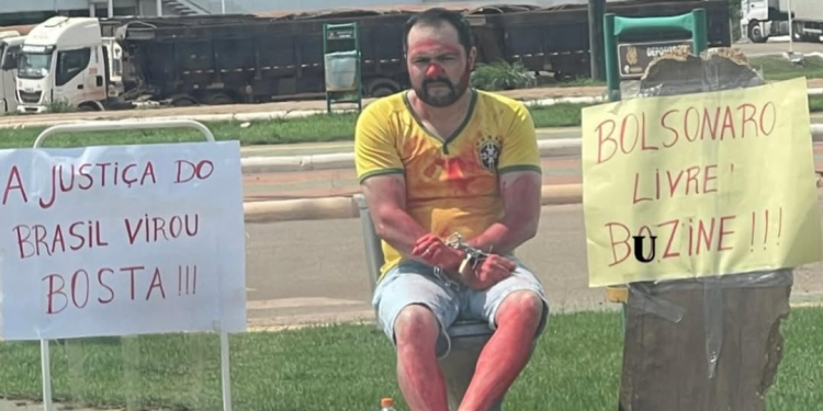 O homem apareceu em vídeos acorrentado a um vaso sanitário, segurando cartazes e pedindo apoio dos motoristas que passavam pelo local. Foto: Reprodução